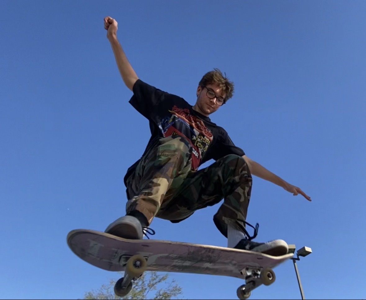 Rohan mid-air on a skateboard against a blue sky